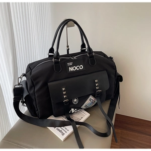 Detail of black canvas travel bag with rivet decor and adjustable shoulder strap