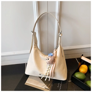 Detail of off-white crescent hobo bag featuring pebbled texture and cute monkey keychain