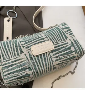 Close-up of green and white geometric canvas pattern with silver chain and leather trim