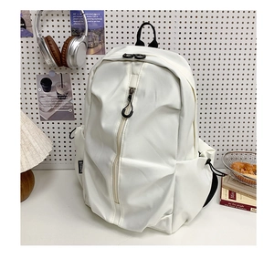 White nylon backpack with vertical zipper detail against a minimalist desk setup