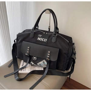 Close-up of black nylon travel bag featuring rivet details and vintage patch embroidery