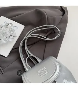 Detail of silver metallic backpack with embossed text on dark gray fabric suit background