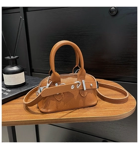 Detailed macro view of brown lychee grain leather mini bag with silver buckle on wood