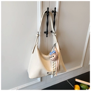 Close-up of beige hobo bag with litchi texture leather and brown plush monkey charm