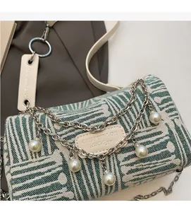 Detail of green striped cylinder tote with silver chains and pearl charms