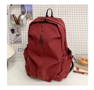 Detail of burgundy backpack with vertical zipper and brand tag on a creative white background
