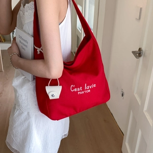 Detail of red canvas tote bag with white embroidery and matching small hanging pouch