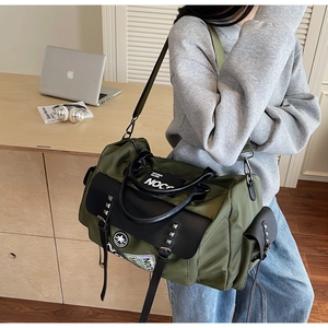 Detail of army green travel bag with buckle pocket and NOCO lettering on nylon surface