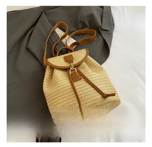 Detail of a straw bucket backpack with brown leather trim and gold metal hardware