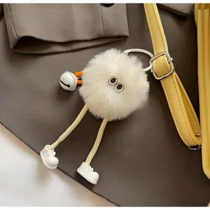 Gros plan d'un pendentif de sac monstre en peluche blanche avec de grands yeux et grelot