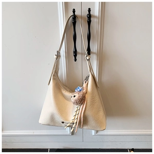 Detail of cream leather hobo bag with monkey plush charm and adjustable strap