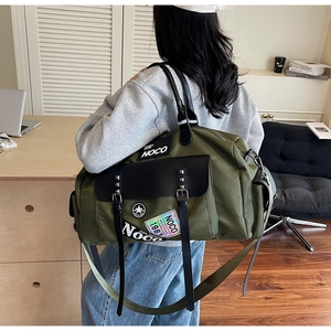 Detail of army green large canvas travel bag featuring durable handles and brand patches