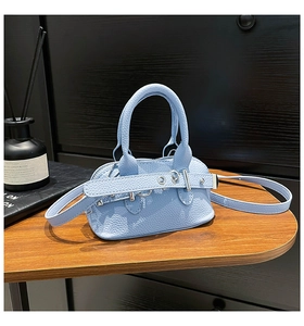 Detail of light blue pebble grain leather shell bag with adjustable shoulder strap