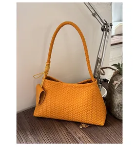 Macro detail of yellow woven faux leather shoulder bag with decorative strap ornament