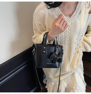 Détail du sac seau noir plissé brillant avec breloque chien et lettrage du logo