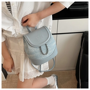Detail view of light blue leather and denim backpack with embossed text and silver chain
