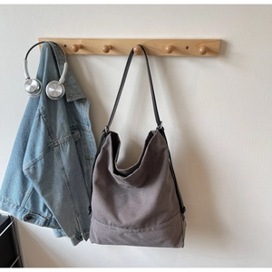Detail view of large taupe canvas tote bag hanging with lifestyle accessories