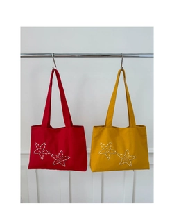 Detail of red and yellow canvas tote bags with double star pearl decorations on metal rack