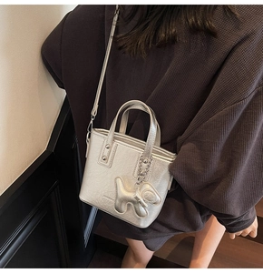 Detail of silver metallic mini tote bag with puppy charm and detachable shoulder strap