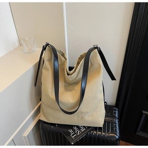 Detail of khaki canvas tote bag with black leather straps on a vintage suitcase
