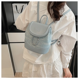 Detail shot of light blue mini backpack showing textured fabric and silver chain accent