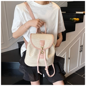 Dettaglio dello zaino in paglia intrecciata con finiture in pelle rosa e coulisse