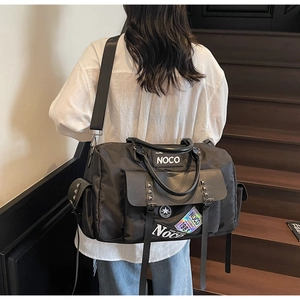 Detail of black large travel bag with cool patches and studs on indoor wooden stairs