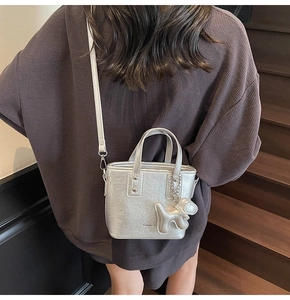 Sac seau argenté métallisé à texture plissée et breloque chien porté par un mannequin