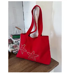 Detail view of red canvas tote bag with silver star rivets on a rustic wooden table