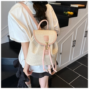 Dettaglio dello zaino in paglia intrecciata con spallacci rosa e chiusura a fibbia