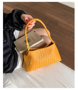 Detailed close-up of yellow woven shoulder bag with knotted handle and braided texture