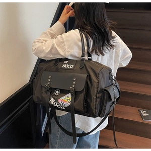 Close-up of black canvas travel bag with rivet details and shoulder strap on stairs