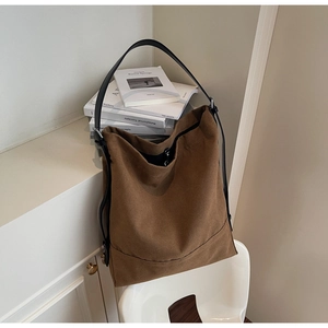 Detail view of brown canvas bucket bag with black leather strap and silver metal ring