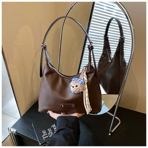 Close-up of brown faux leather shoulder bag with pleated texture and plush charm accessory
