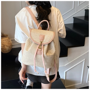 Dettaglio dello zaino in paglia intrecciata con spallacci in pelle rosa e chiusura in metallo