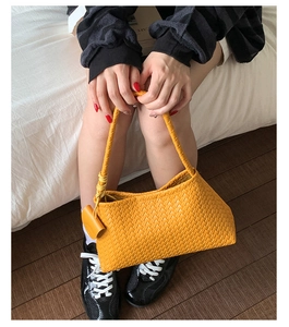 Detailed view of yellow hand-woven leather bucket bag with Intrecciato craft and handle