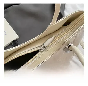 Detail of silver polished hardware and zipper on creamy white crocodile texture handbag