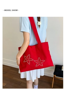 Detail view of the red oversized tote bag featuring distinctive star stud embellishments