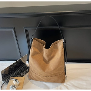 Close-up of a large canvas bucket bag with laptop and books in a lifestyle setting