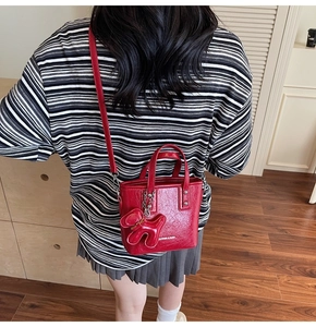 Détail du mini sac seau en cuir rouge brillant avec breloque chien et bandoulière