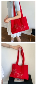 Detail view of red canvas tote bag with decorative silver metal star rivets
