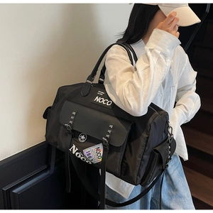 Model wearing a large black nylon sports travel bag with vintage NOCO 1983 patch
