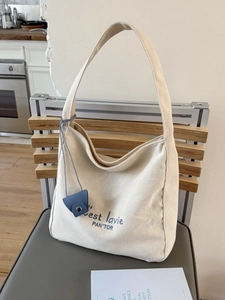 Minimalist canvas tote bag with French slogan and a blue leather mini pouch detail
