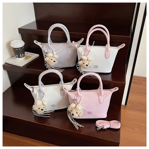 Sacs seaux chic en cuir texturé aux tons pastels avec charms ours sur marches en bois