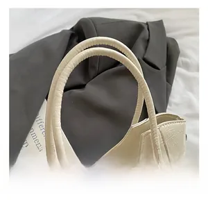 Detail shot of the comfortable cream-colored padded handle on a wrinkled texture handbag