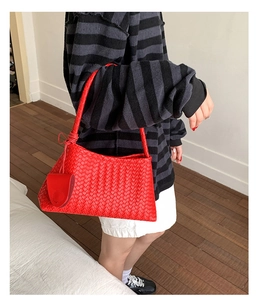 Detail of red woven texture shoulder bag with knotted strap and small leather pendant