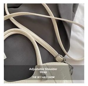 Detail of adjustable shoulder strap with silver buckle on white crocodile pattern handbag