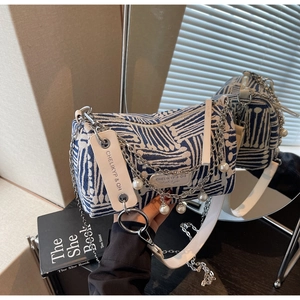 Detail of blue and white geometric canvas barrel bag with pearl and chain decoration