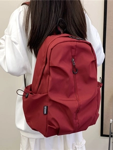 Minimalist deep red backpack for travel featuring a vertical zipper and drawstring side pockets
