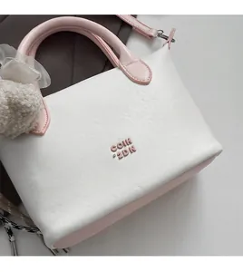 Détail du sac à main en cuir grainé blanc et rose avec logo gaufré et charme en peluche
